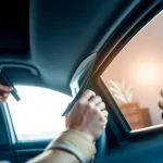 Applying window tint Chattanooga with precision in a bright car interior.